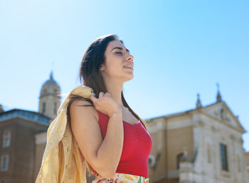 Smiling young woman against clear sky