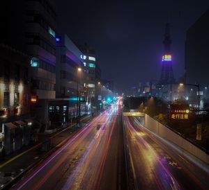 Light trails on road amidst buildings in city at night