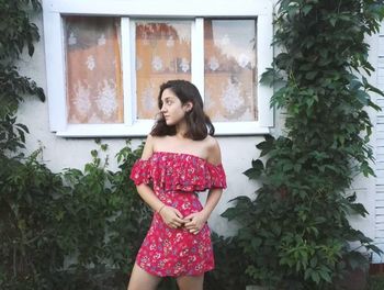 Portrait of young woman standing against plants