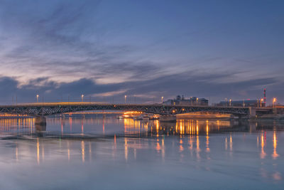 Illuminated bridge over river against sky at night