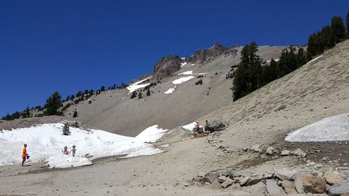 People on snowcapped mountain against clear blue sky