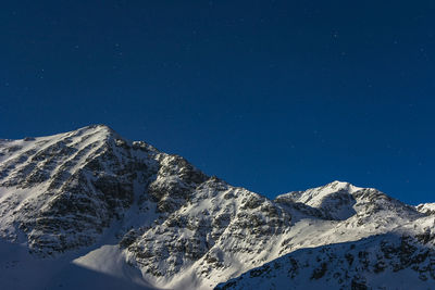 Aerial view of snowcapped mountains against blue sky