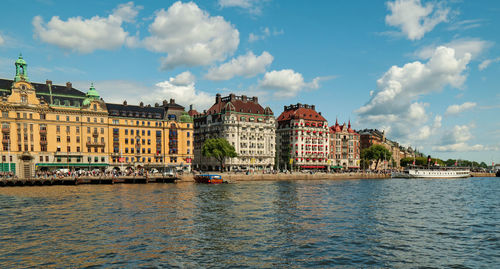 View of buildings by sea against cloudy sky