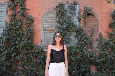 Portrait of a young woman standing against wall