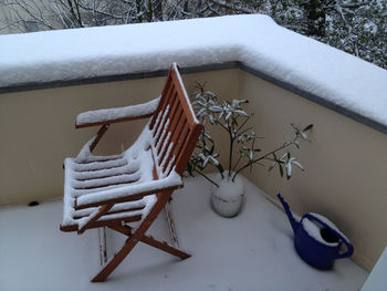 High angle view of chair and potted plant covered with snow in balcony