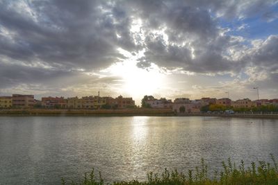 Scenic view of river by buildings against sky