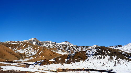 Scenic view of snowcapped mountains against clear blue sky