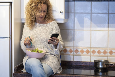 Portrait of young woman using mobile phone on table