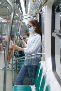 Woman using phone while standing in train