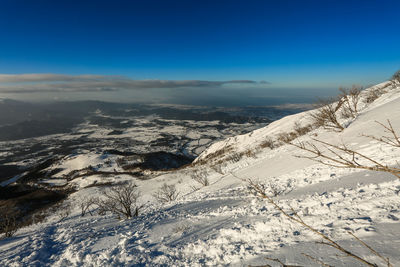 Aerial view of snow covered landscape against blue sky