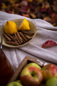 Close-up of  sliced lemon, apples and cinnamon sticks on table