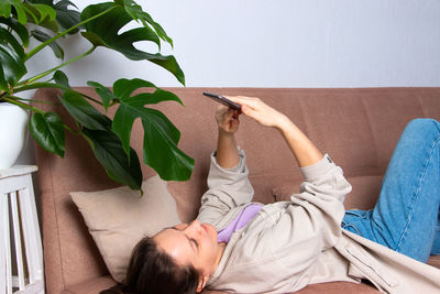 Young woman at home on the couch with a phone in her hand.