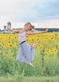 Young lady jumping in a field of sunflowers