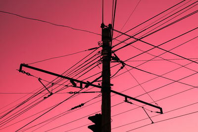 Low angle view of silhouette electricity pylon against sky during sunset