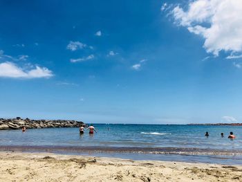 People on beach against blue sky