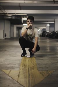 Portrait of young man crouching in parking lot