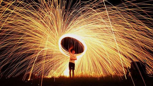 Full length of man with illuminated wire wool at night