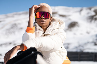 Portrait of woman wearing sunglasses while standing on snow