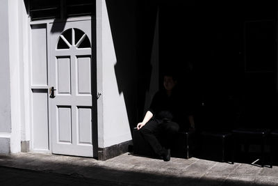 Portrait of young woman sitting against wall