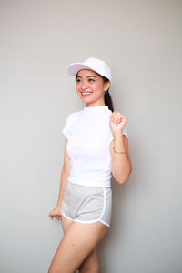 Portrait of smiling young woman standing against white background