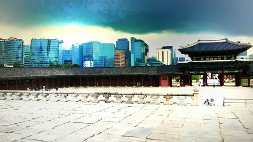 Modern buildings in city against cloudy sky