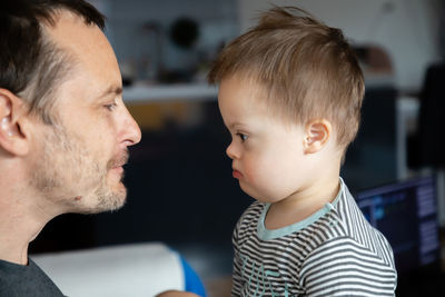 Side view of mid adult man looking at son with down syndrome