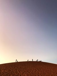 Group of people on desert against clear sky