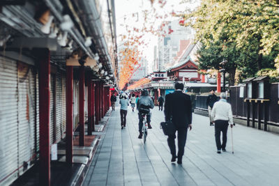 Rear view of people walking on street in city