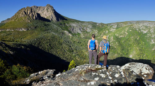 Rear view of male hikers standing against mountains