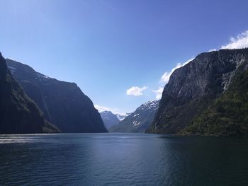Scenic view of lake and mountains against blue sky