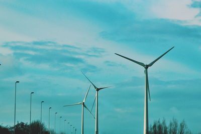 Low angle view of wind turbines against sky