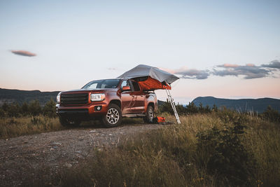 Red pick up truck with roof top tent camping in maine woods with view