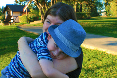 Portrait of smiling mother with son on grassy field