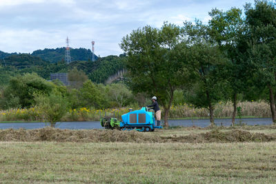 Man on car on field against sky