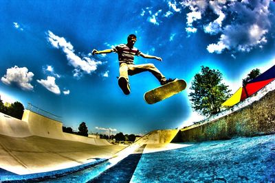 Low angle view of woman jumping against clear sky