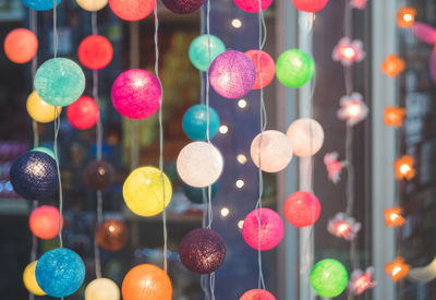 Close-up of illuminated lights hanging on window at night