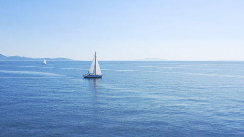 Sailboat sailing in sea against clear sky