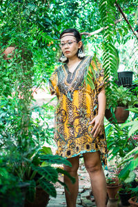 Young woman standing against plants