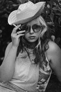 Portrait of woman wearing hat while smoking cigarette outdoors