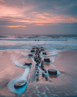 Scenic view of sea against cloudy sky during sunset