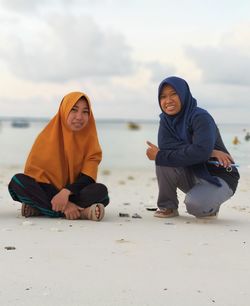 Rear view of young women sitting on beach