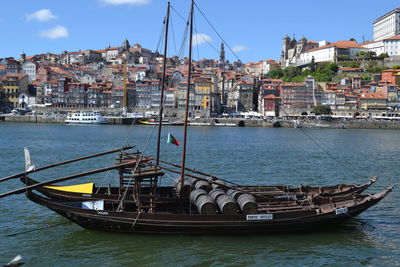 Boats moored at harbor against sky in city