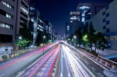 Light trails on city street by buildings at night