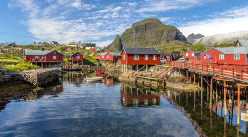 Houses by lake and buildings against sky