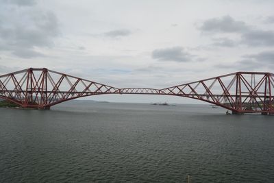 Bridge over river against cloudy sky