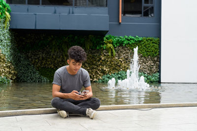 Full length of boy sitting in water