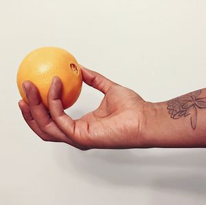 Close-up of hand touching orange
