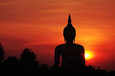 Silhouette buddha statue against sky during sunset