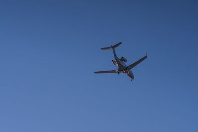 Low angle view of airplane against clear blue sky