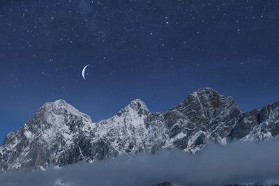 Low angle view of snowcapped mountains against sky at night